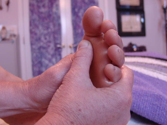 Hands massaging bare foot on purple blanket